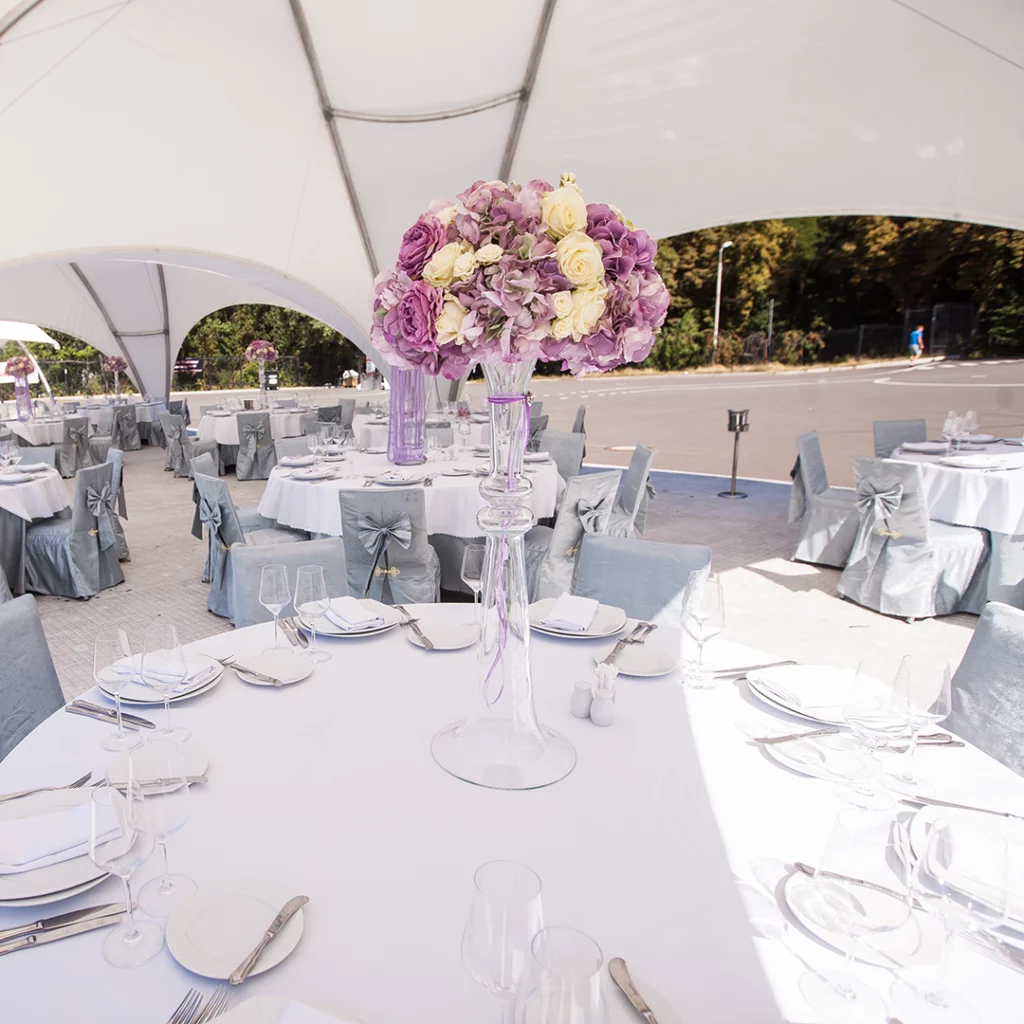 Organisation Événementiel 360 , Location de chapiteau et mobilié : Centre de table floral mauve et blanc pour une réception en extérieur sous le dôme Tent'Action biarritz