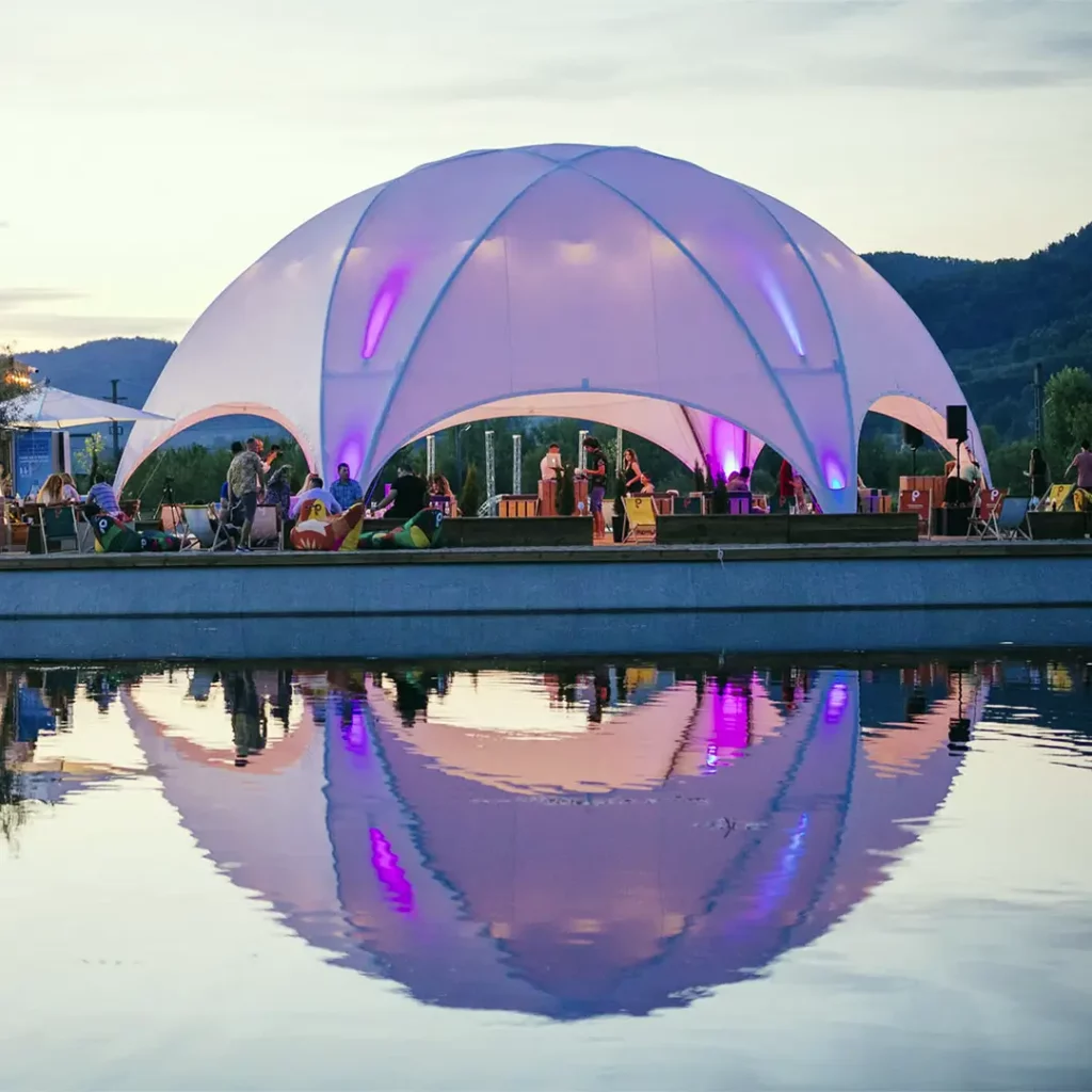 Location de chapiteau Hexadome de 100m² au bord d'un lac, avec un concert au coucher du soleil, illustrant l'expertise d'organisation d'événements de Tent'Action.