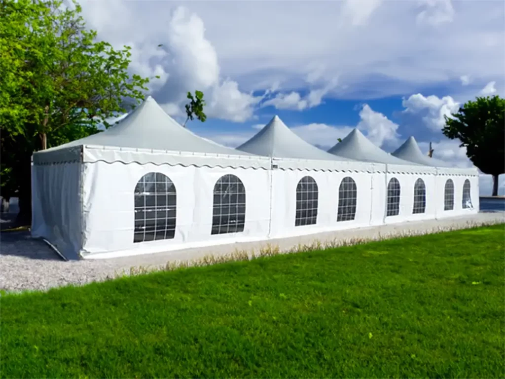 location pagode, grande tente élégante blanche de Tent’Action avec des sommets pointus et des côtés vitrés, installée sur une pelouse verte sous un ciel bleu clair.