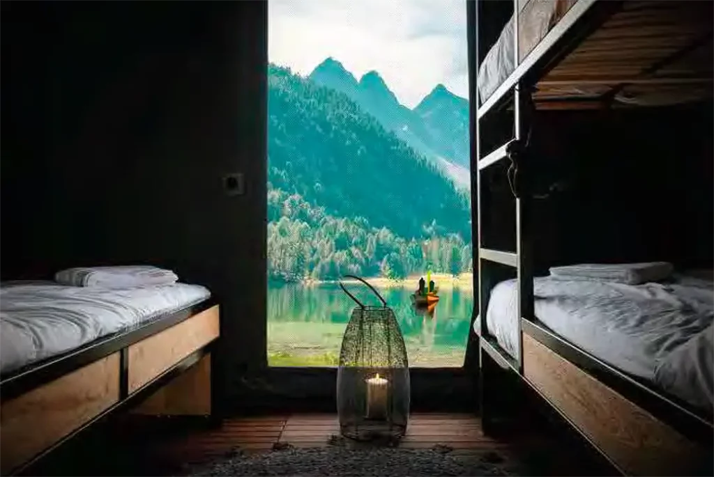 Deux lits simples dans un lodge de luxe avec une vue imprenable sur un paysage montagneux et un lac.