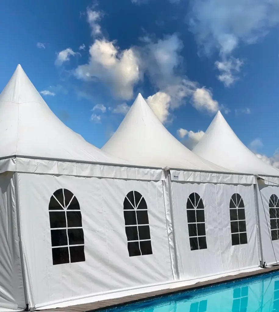 Tente pagode blanche de Tent’Action pour cérémonies, installée au bord d’une piscine sous un ciel bleu nuageux.