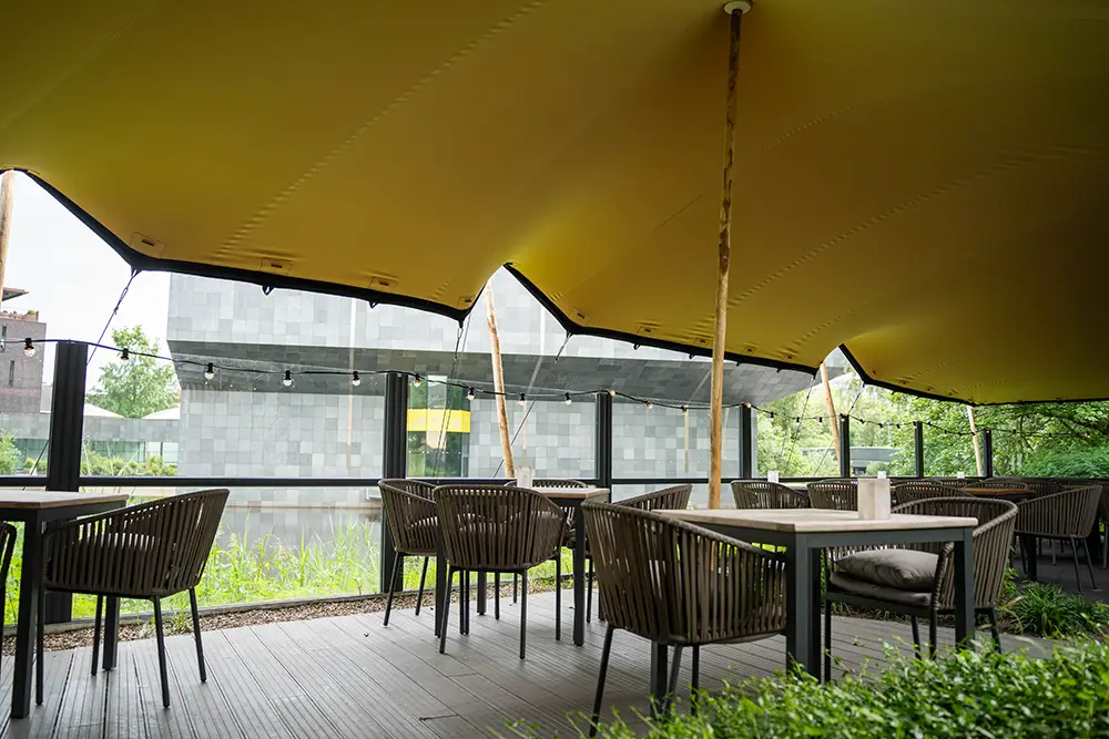 Intérieur de tente nomade avec parquet bois, tables et chaises en osier – événement dans les Landes