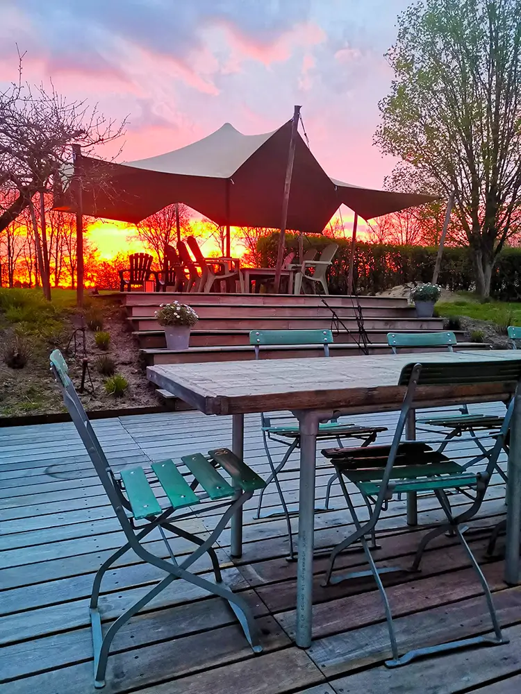 Tente nomade événementielle sur terrasse en bois avec table de jardin et coucher de soleil dans Les Landes
